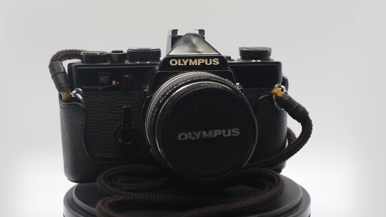 A zooming shot of an old vintage Olympus camera in a white box while rotating.