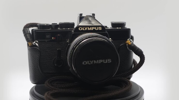 A zooming shot of an old vintage Olympus camera in a white box while rotating.