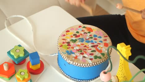 child playing a colorful toy drum with wooden toys