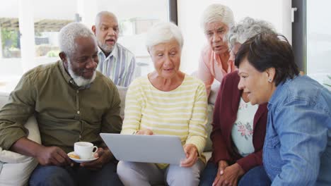 Happy-senior-diverse-people-talking-and-using-laptop-at-retirement-home