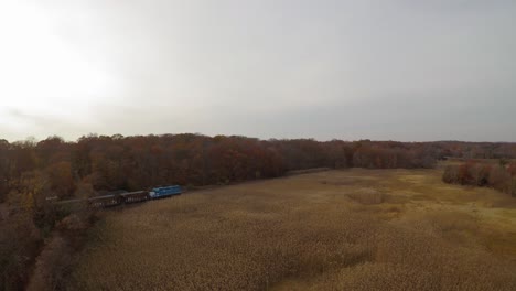 Aerial-Forward-Dolly-Shot-of-Boulder-Locomotive-Running-Through-Wetlands-in-Autumn