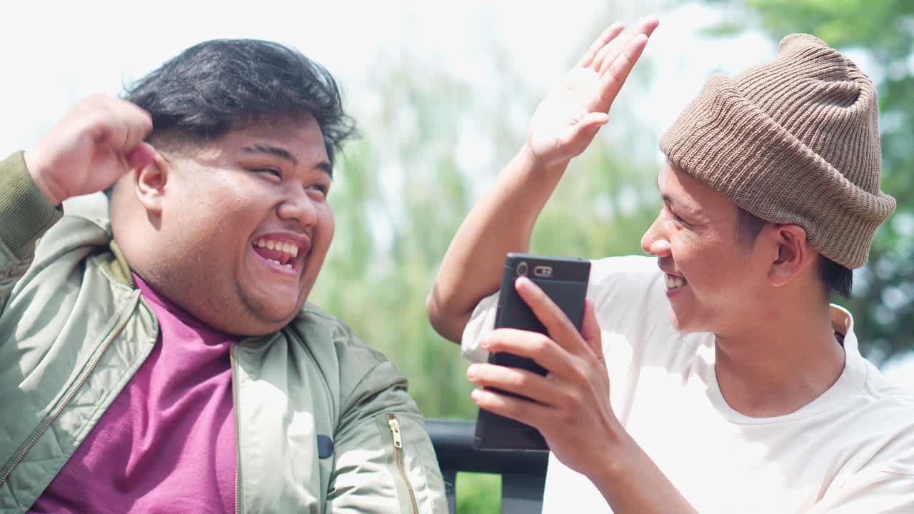 Two Young Asian College Students Using Tablet And Smartphone And Giving High Five To Each Other Celebrating Victory