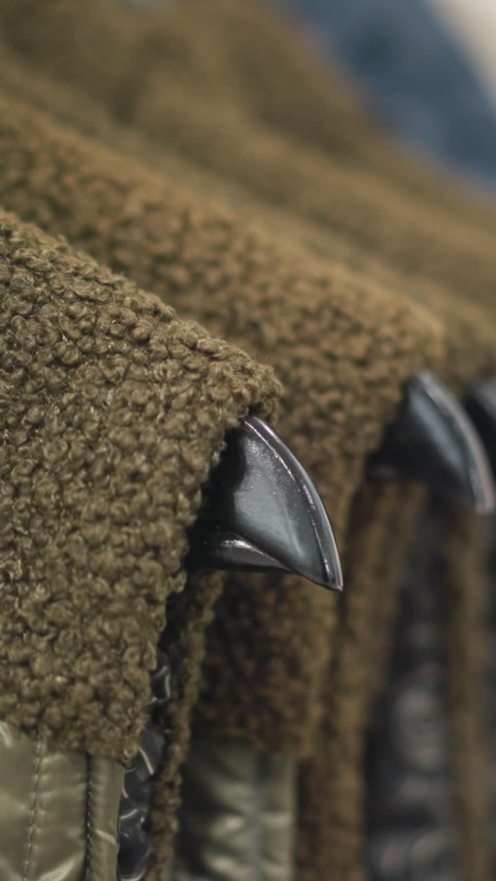 primer plano de chaquetas cuidadosamente dispuestas en varios tonos de tierra, con lana suave y materiales acolchados en colgadores negros elegantes, haciendo hincapié en detalles de textura, diseño moderno de ropa exterior