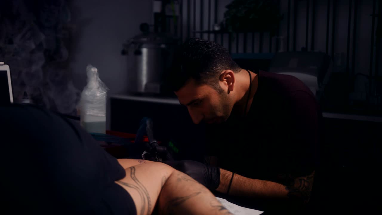 Tatuatore che lavora sul tatuaggio di un cliente in uno studio di tatuaggi professionale