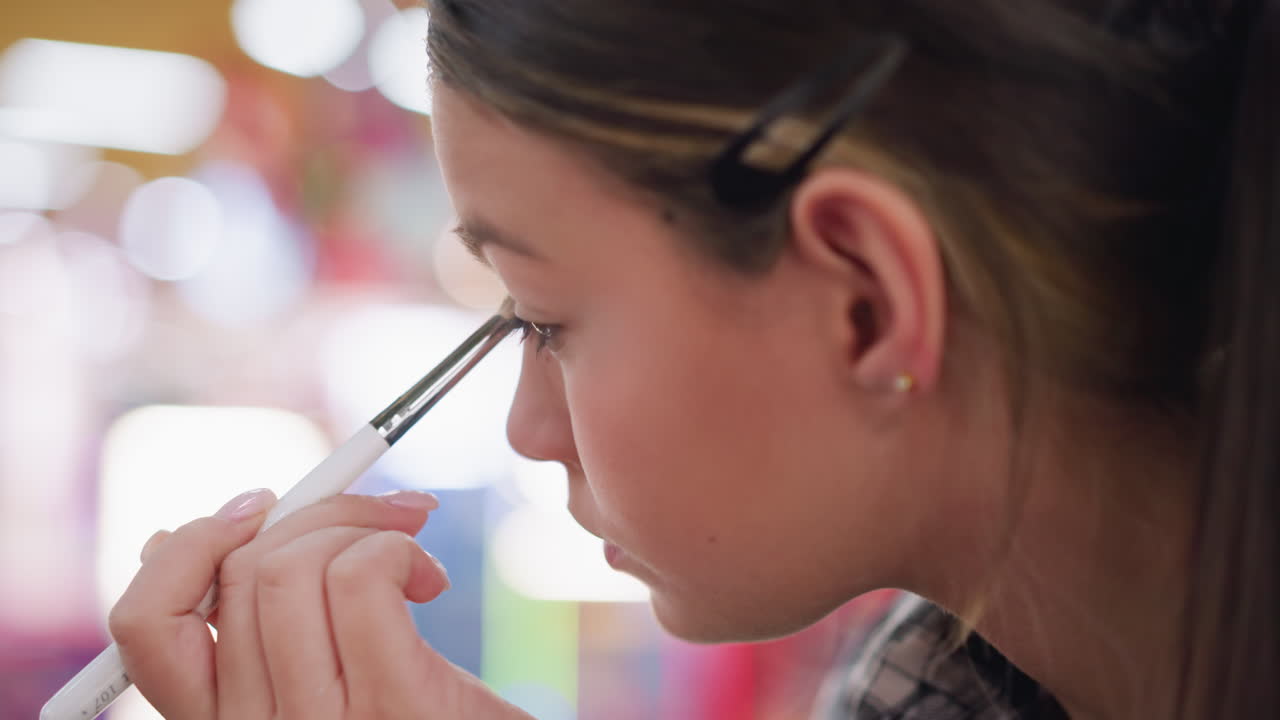 joven artista polvo en su cara usando pincel, aplicando cuidadosamente maquillaje con trazos precisos en close-up, destacando la técnica de maquillaje y el proceso de aplicación