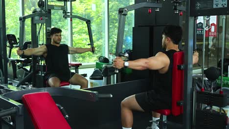Athletic man performing chest fly exercise on machine in sunlit modern gym, side view