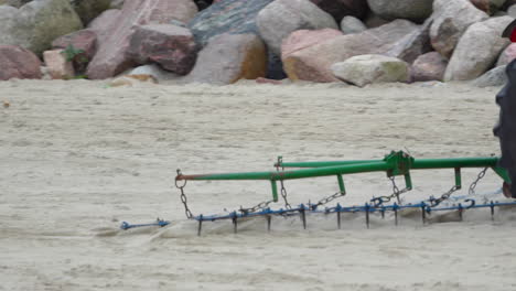 tractor dragging harrow on the sand