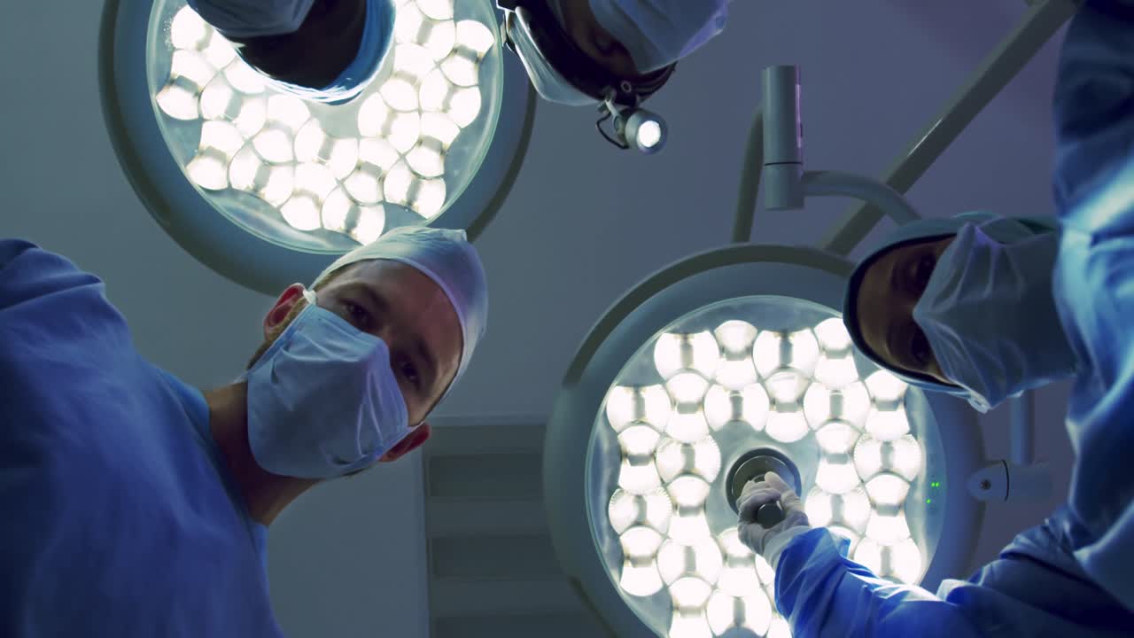 Opadgående vinkel af multietniske kirurger, der udfører en operation på operationsstuen på et hospital.