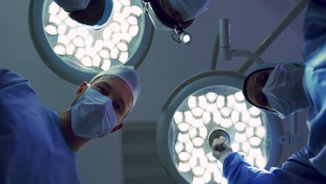 vista hacia arriba de cirujanos multiétnicos que realizan cirugías en la sala de operaciones del hospital