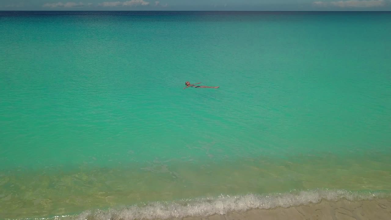 고요하고 따뜻한 열대 바다에 떠 있는 여자. 공중선