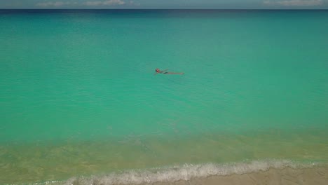 mujer flotando en un océano tranquilo, cálido y tropical. aéreo