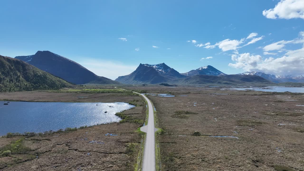 Driving forward on Gimsoy island road in lofoten, then turning into raising aerial revealing endless road and landscape
