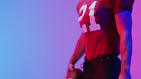 Video-of-caucasian-american-football-player-with-ball-and-copy-space-over-neon-purple-background