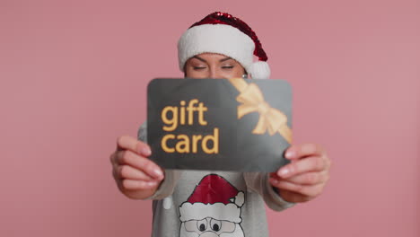 Woman-showing-pointing-on-gift-discount-certificate-Christmas-voucher-coupon-for-store-holidays-sale