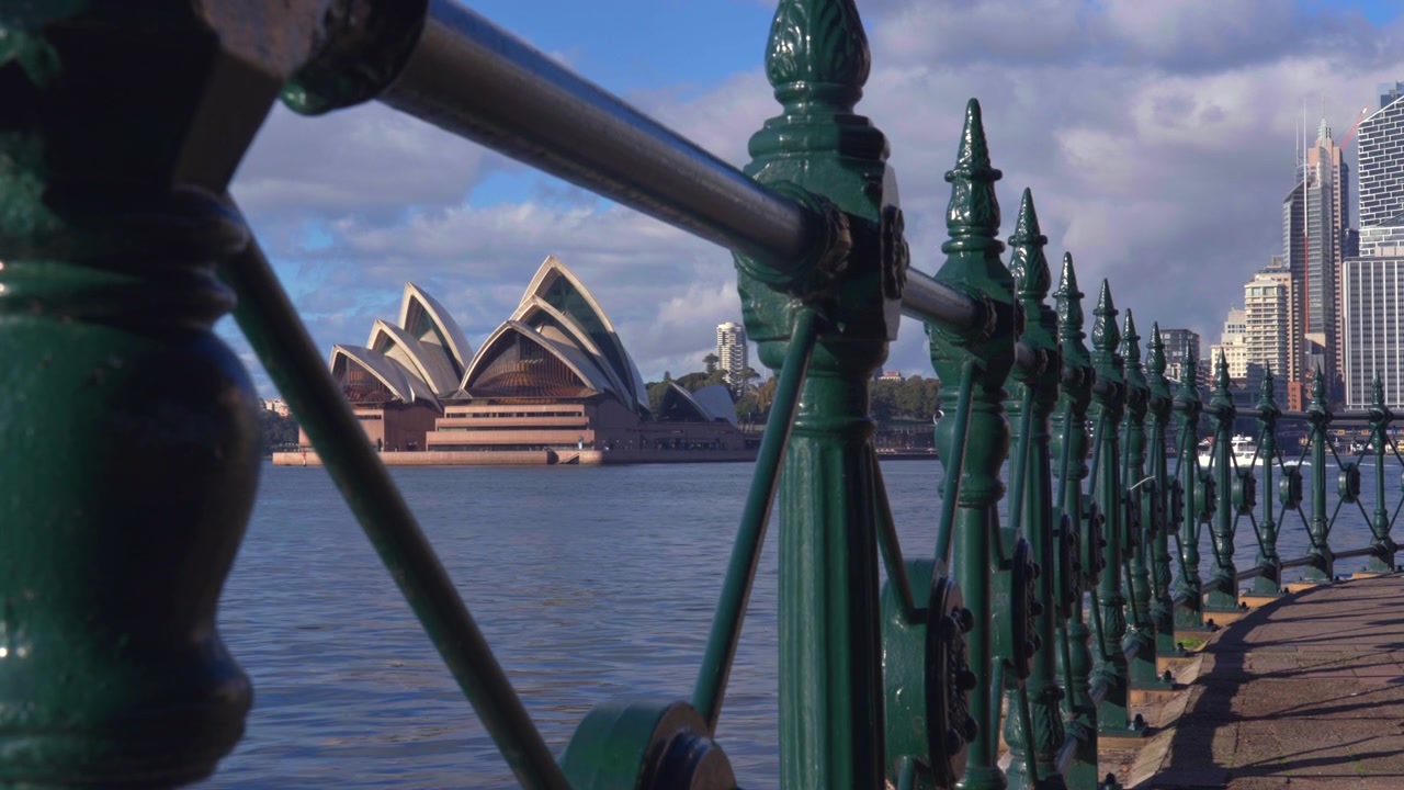 Nærbillede langs det historiske havnerækværk med Sydney Opera House og byens bygninger synlige på den anden side af vandet. Sydney, New South Wales, Australien