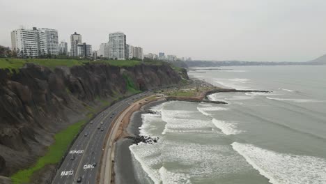 El-Atractivo-Costero-De-Miraflores,-Lima:-Un-Dron-Se-Desliza-Sobre-La-Carretera,-Capturando-La-Vibrante-Energía-Del-Distrito.