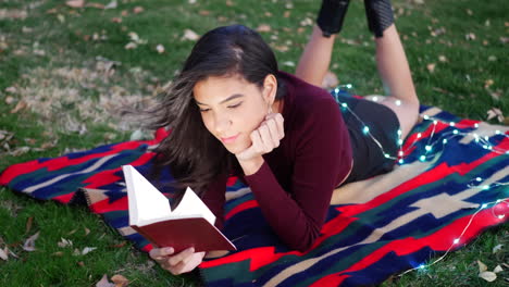 a hispanic woman university student laying outdoors reading and studying a school textbook on a college campus slow motion