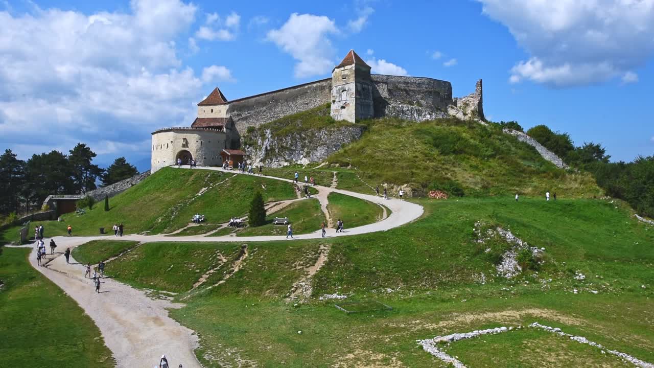 BRASOV, ROMANIA - AUGUST 17, 2019: Timelapse of walking people near Rasnov Citadel in the morning. General view