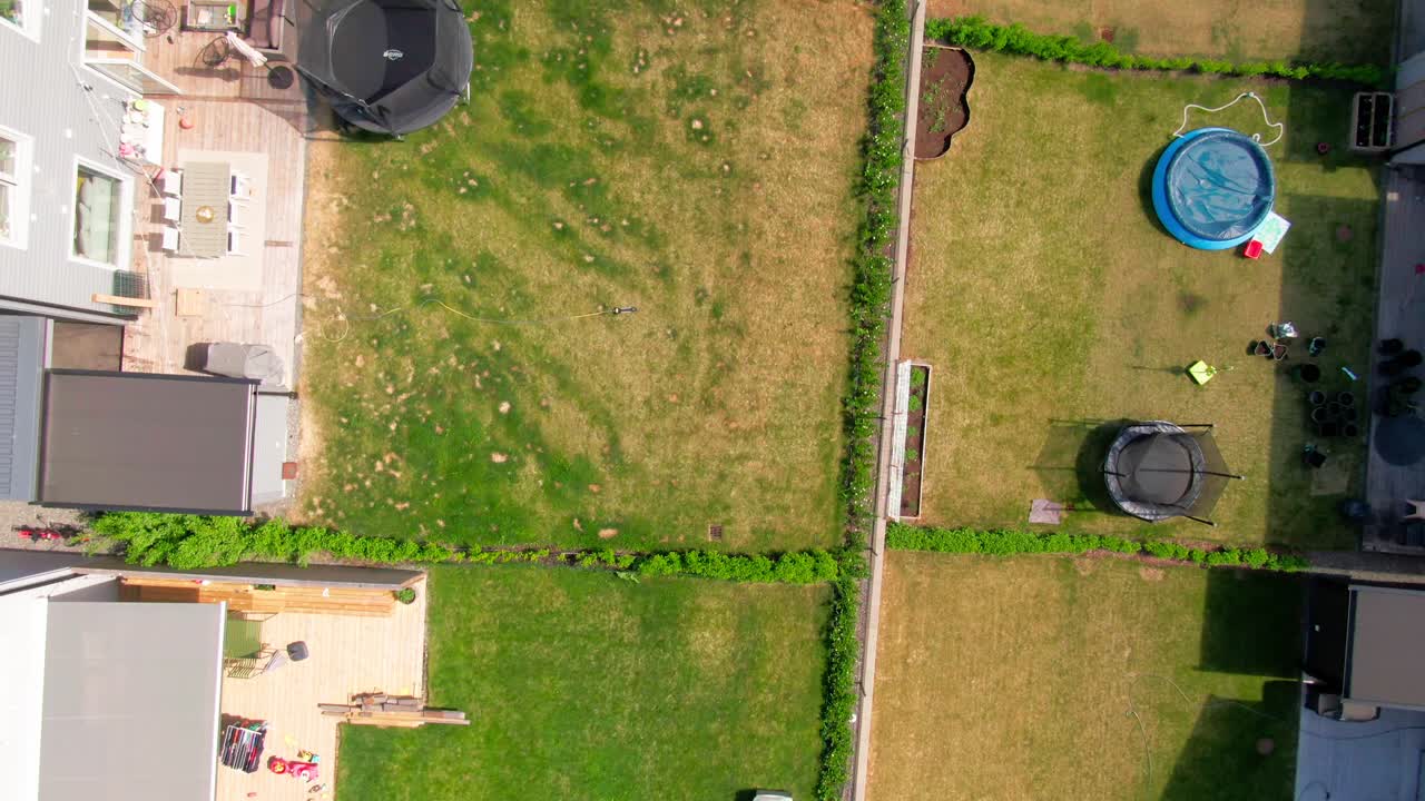 Overhead close-up of two adjacent fenced-in private backyards featuring trampolines, a pool, and grass