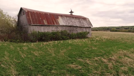 a very old barn surrounded by farm fields