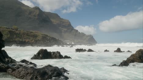 peligrosas olas oceánicas en movimiento lento aplastando rocas volcánicas afiladas cerca de punta negra, buena vista del norte, tenerife, islas canarias en primavera