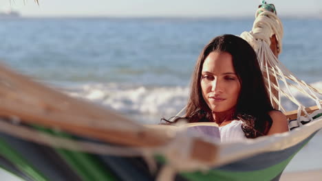 Cute-brunette-woman-reading-a-book-on-a-hammock