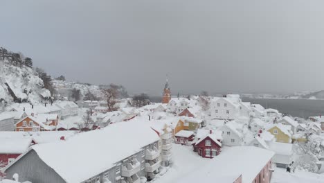 Vista-Lejana-Del-Campanario-De-La-Iglesia-De-Kragero-Y-Casas-Nevadas-En-Invierno-En-El-Condado-De-Telemark,-Noruega