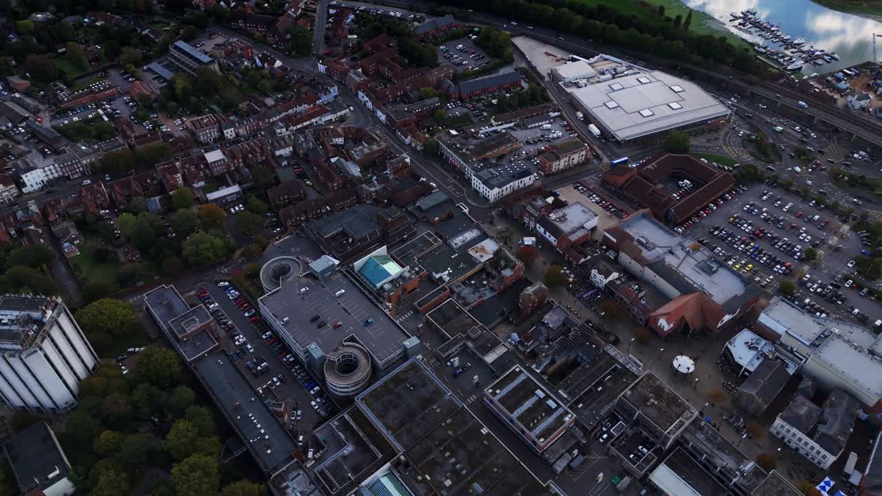 Aerial drone footage pans left over Fareham town centre in autumn, capturing roads, cars, trees, and nature glowing warmly in golden sunset light across the scenic English landscape