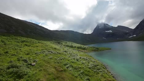 FPV-drone-glides-gracefully-along-a-mountain-lake,-leading-to-a-majestic-peak,-capturing-the-serene-beauty-of-alpine-landscapes-in-cinematic-detail