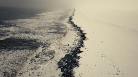 cinematic drone moves show black sand beach in iceland filmed by drone in snowy conditions