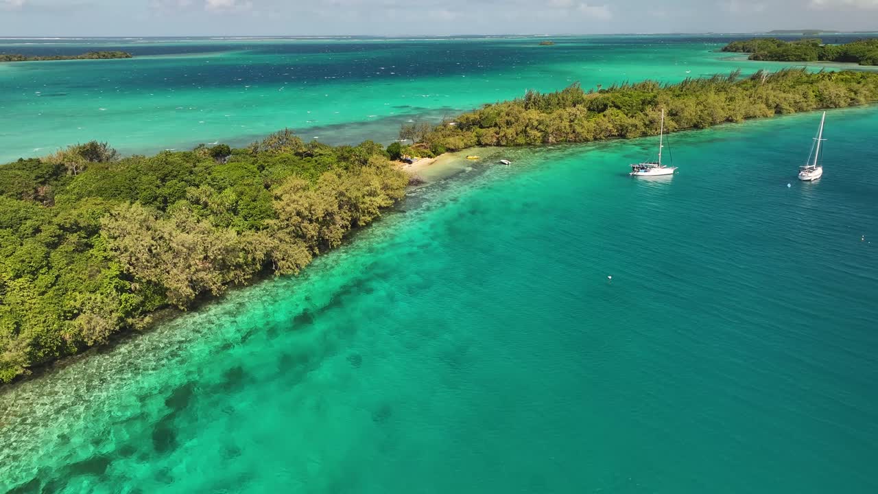 Small sandy beach in remote Pacific Island, coral reef and sailing boat. Beautiful sunny day in Tonga.