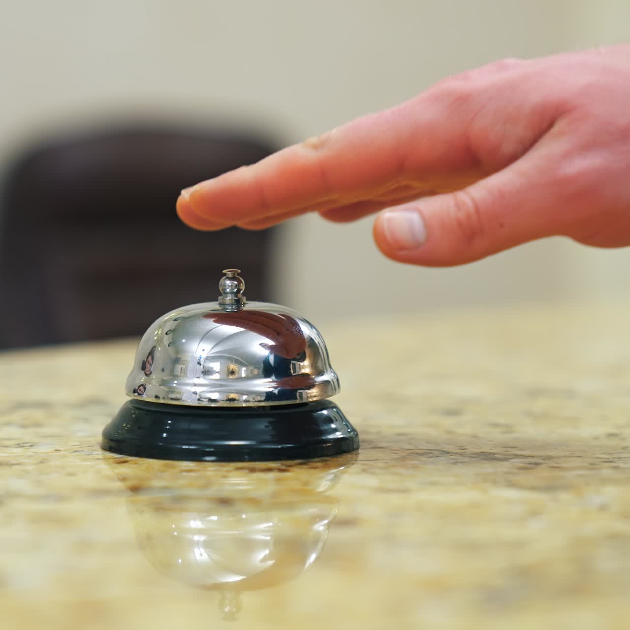 Calling the receptionist. Hand of a tourist in the reception of a hotel presses the bell button. Close-up