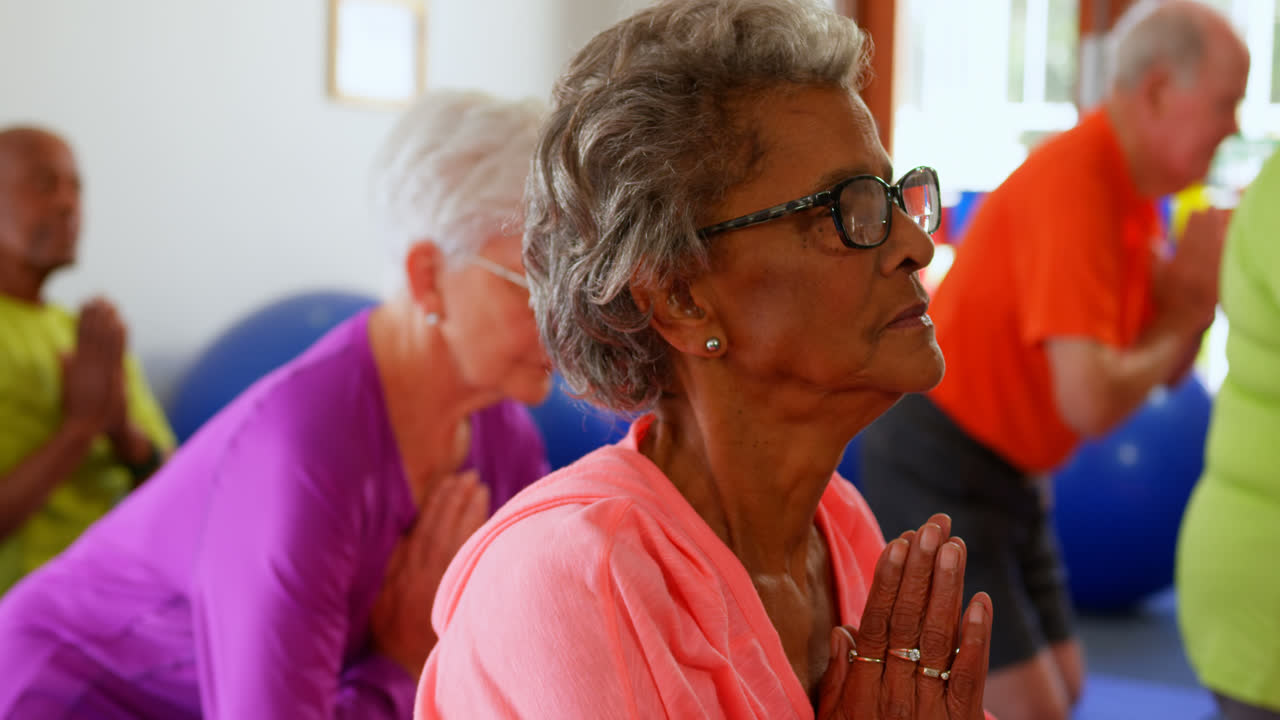 Side view of active mixed-race senior people performing yoga in fitness studio 4k 