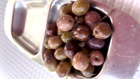 vertical close-up view of olives in a silver scale