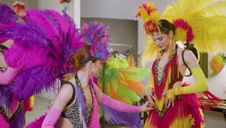 pretty cabaret girls with feather colorful dresses getting ready