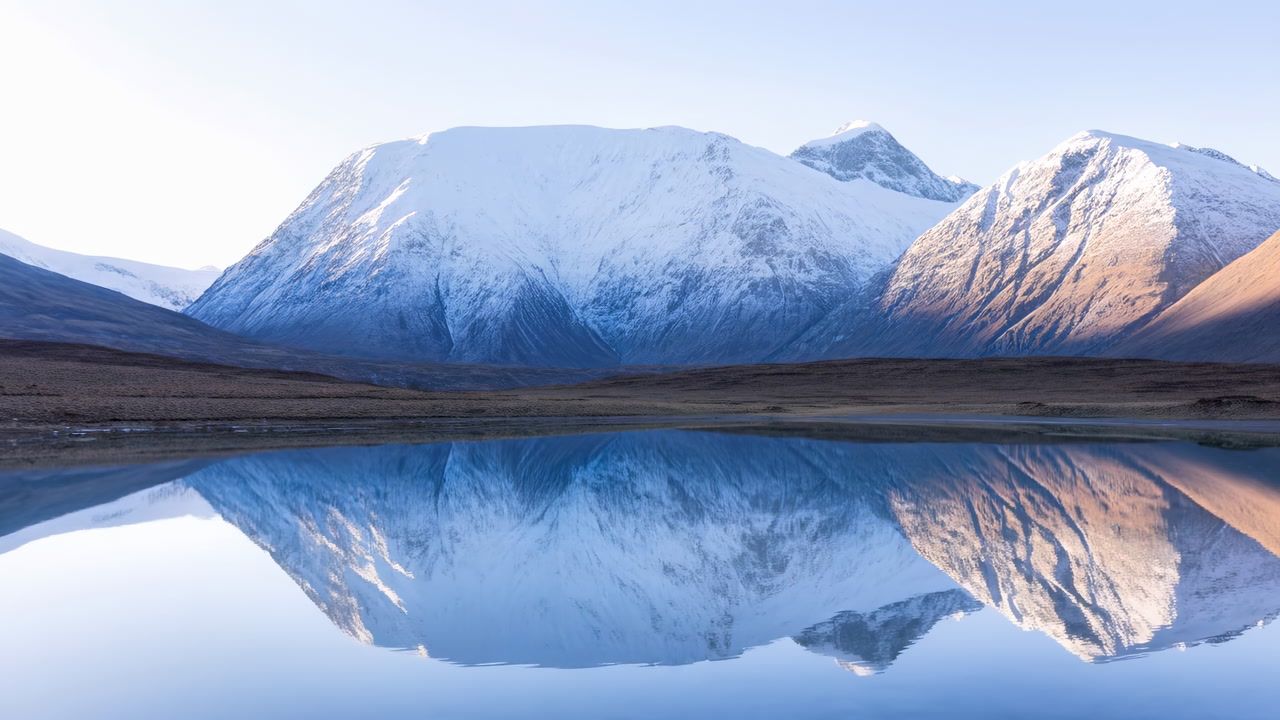 Snow Covered Mountain Reflected In Lake, Soft Sunrise Light Bathing Alpine Ridge And Glassy Water Mirror,