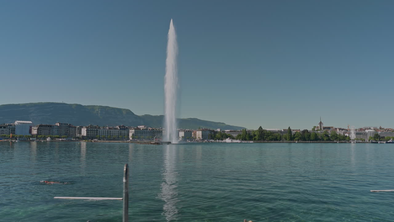 Peaceful morning in Geneva with the iconic Jet d’Eau rising from the lake, calm waters reflecting the clear sky, and the city slowly coming to life in the morning light.