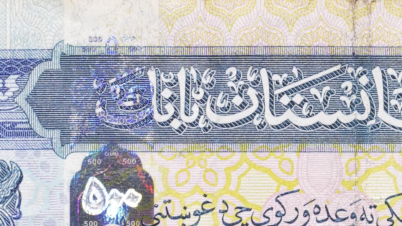Macro pan across a 500 afghani note, highlighting Central Bank Arabic text, guilloche and a holographic patch