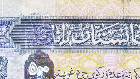 macro pan across a 500 afghani note, highlighting central bank arabic text, guilloche and a holographic patch