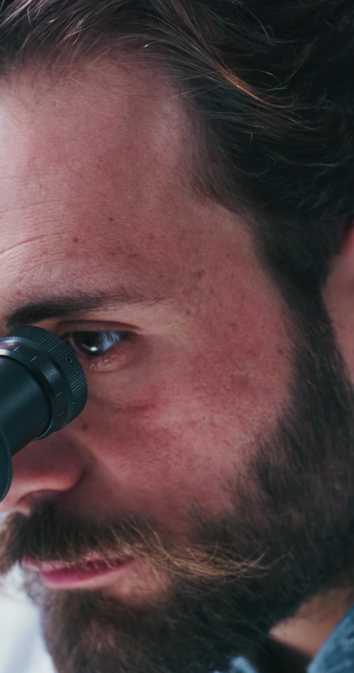 Scientist Looking Through Microscope in Laboratory