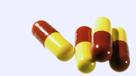 red and yellow capsule tablets dropping and bouncing close up