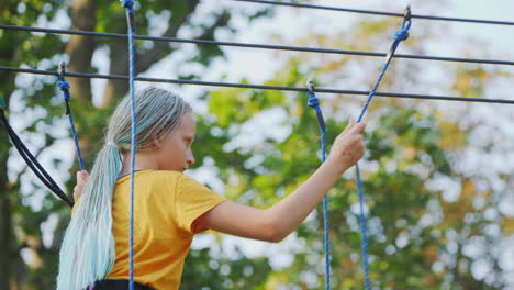 a child climbs ropes high in the trees - having fun in a rope city in an amusement park