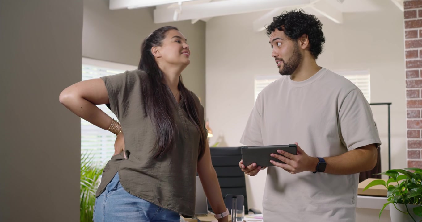 African American coworkers woman in olive top pointing man scrolling tablet discussing choices home