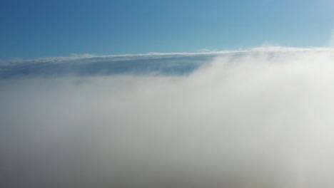 slow aerial descend through dense morning fog layer over land, latvia