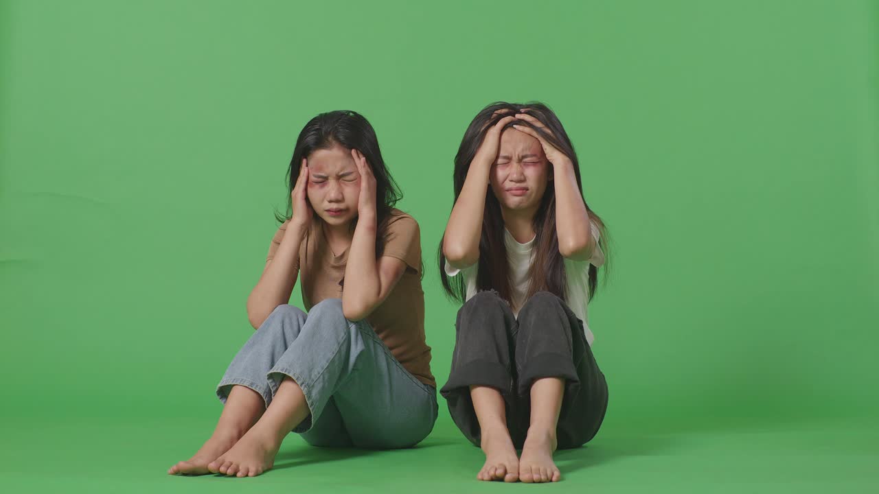 젊은 아시아 여성들의 몸은 폭력의 희생자입니다. 몸에 이 있고, 스트레스를 받고, 머리가 아습니다. 녹색 스크린 배경 스튜디오에 앉아있는 동안.
