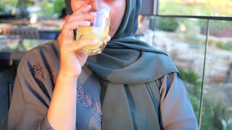 woman in hijab drinking juice at a cafe