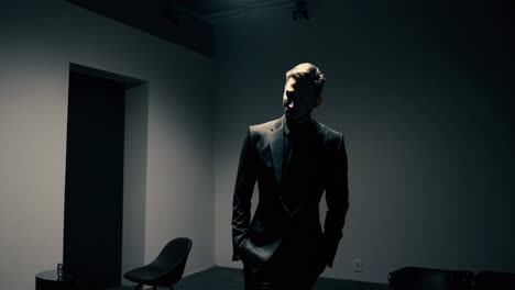 man in a dark suit in a dramatically lit room