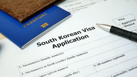 formulario de solicitud de visado de corea del sur con pasaporte y bolígrafo