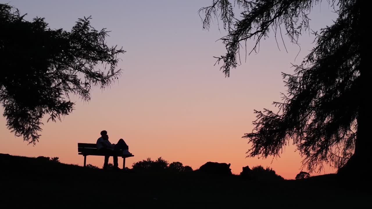 Silhouette of a person sitting on a bench at sunset