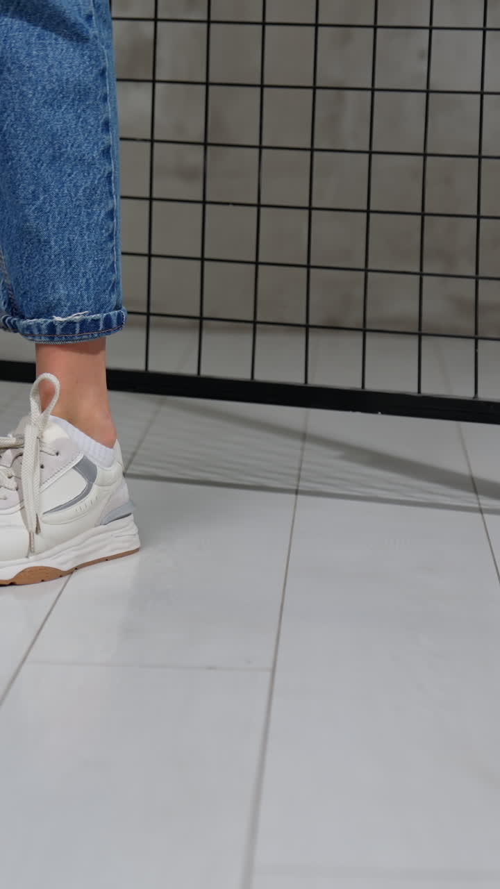 Close-up of White Sneakers on Legs in Jeans